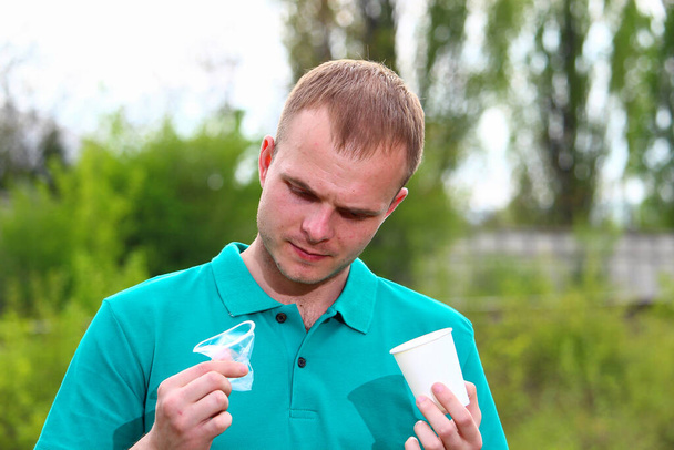 Ein Mann im grünen T-Shirt von Marrs fordert die Ablehnung von Plastikbechern und einer Auswahl von Papier - Foto, Bild