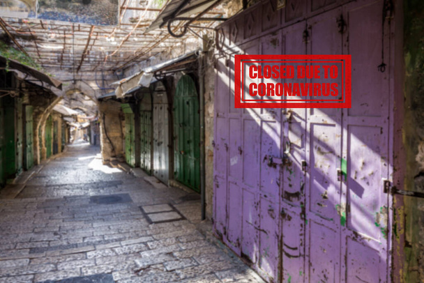 Pusta ulica z zamkniętymi sklepami w Starym Mieście Jerozolimy. Po wybuchu epidemii koronawirusów, rząd izraelski zdecydował się na masową godzinę policyjną, pozostawiając Stare Miasto całkowicie opuszczone.. - Zdjęcie, obraz