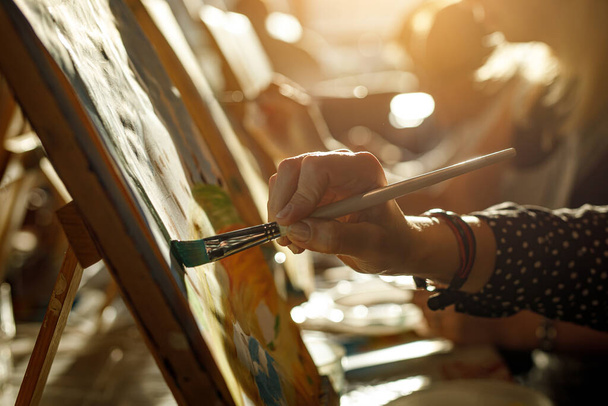 Hand of artist with brush painting picture, sunset light - Φωτογραφία, εικόνα