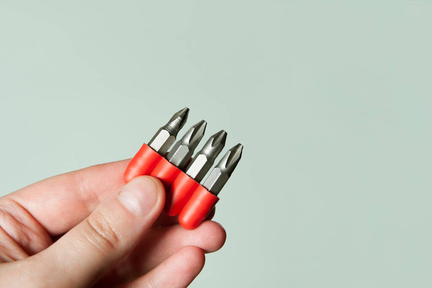 set of screwdriver bits. close-up photo of construction tools. metal repair accessories isolated on grey background. screwdriver bits in woman's hand - 写真・画像