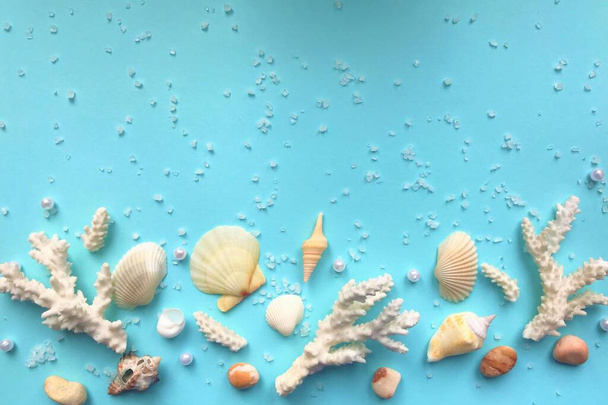 Composição de galhos de coral branco, várias pequenas conchas, pedras, cristais brancos dispersos e pérolas em um fundo turquesa pálido com espaço para texto
 - Foto, Imagem