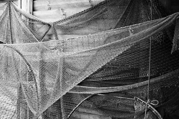 Velhas redes de pesca penduradas em uma parede de madeira
.                          - Foto, Imagem