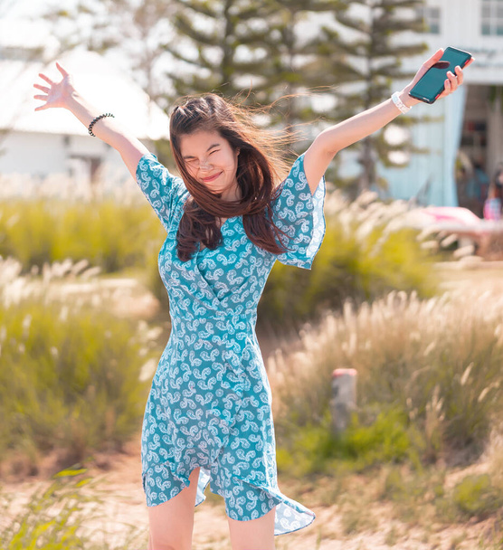 Asyalı kız elini kaldırıyor yaz sert rüzgarını karşılamak için Güzellik vücudunda esiyor - Fotoğraf, Görsel