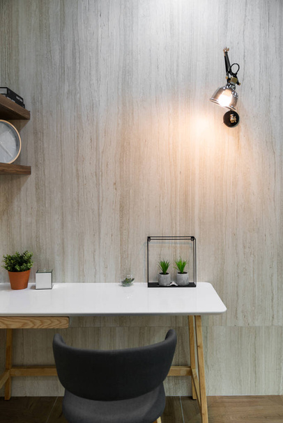 Bedroom working corner decorated with artificial plants and wall lamp with  marble wall in the background /apartment interior - Photo, image
