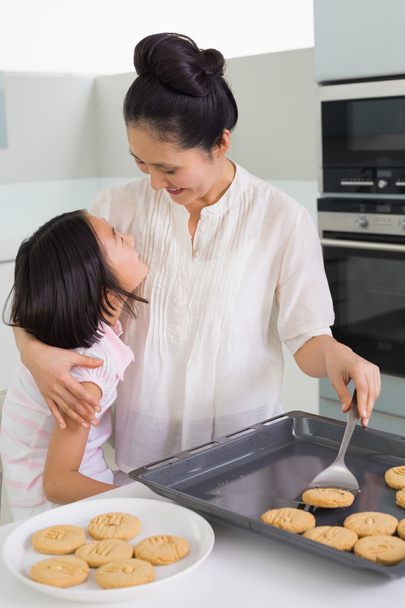 Girl helping her mother prepare cookies in kitchen - 写真・画像