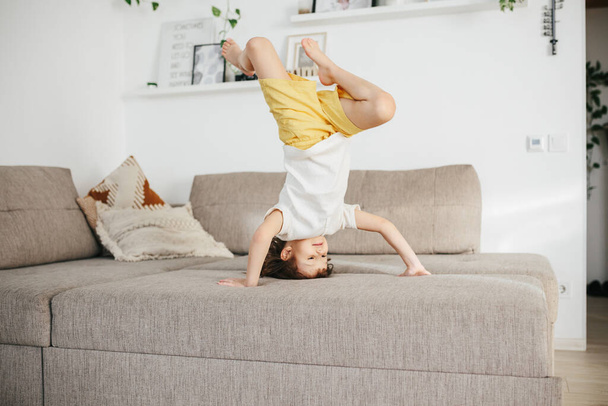 Beautiful little toddler tumbling on sofa at home. Child Learn To Tumble. Tumbling Tutorial. Gymnastics at Home, Tricks - Fotoğraf, Görsel