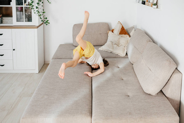 Beautiful little toddler tumbling on sofa at home. Child Learn To Tumble. Tumbling Tutorial. Gymnastics at Home, Tricks - Φωτογραφία, εικόνα