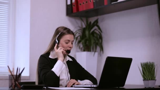 オフィスでマイクとラップトップ付きのヘッドセットでオンラインビデオ会議で話す美しい女性。カスタマーケアサポートチームで働く - 映像、動画