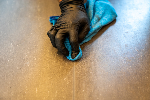 Un primer plano de una lechada de limpieza profesional con un trapo de tela azul y jabón espumoso en un piso de baño de azulejos grises
 - Foto, imagen