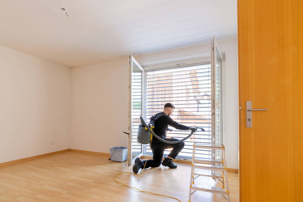 young male professional cleaner vacuuming dirty window blinds and cleaning htem thoroughly - Photo, Image