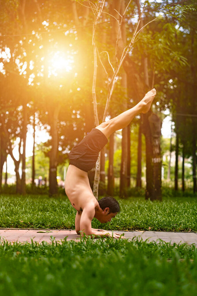 Молодой азиат вытирает пот и занимается йогой в парке. Концепция йоги
. - Фото, изображение