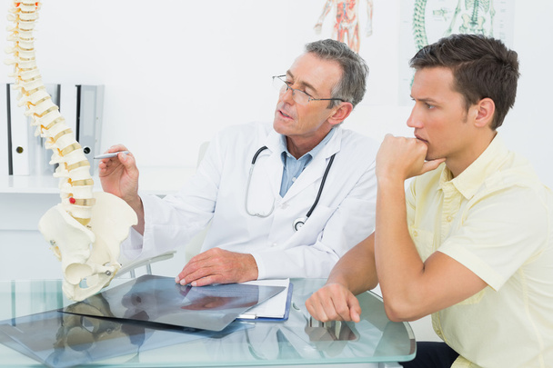 Doctor explaining spine to patient in office - Zdjęcie, obraz