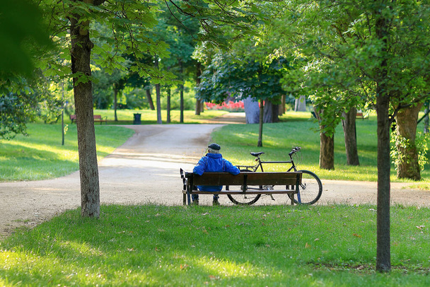 Elderly man sitting on a bench next to his bicycle in a park in Madrid, Spain - Fotografie, Obrázek