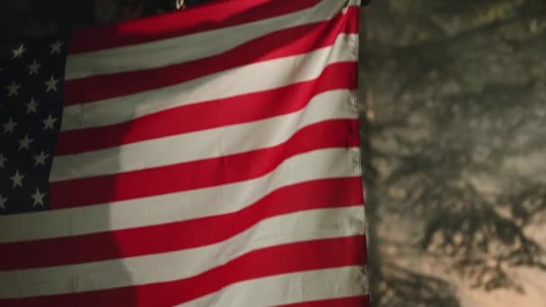 Valkoihoinen sotilas, kolmekymppinen, Amerikan yhdysvaltojen lippu kädessään lähikuva. Amerikka Ylpeä asevoimat. - Materiaali, video