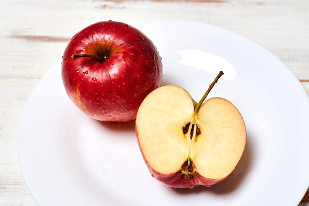 Ripe red apples on a plate on a wooden background. - Foto, afbeelding