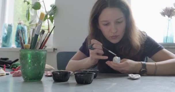 Woman making doll ceramic part. Female sitting and creating ear for doll at home at table. Pottery dolls parts, handmade and creative skills - Footage, Video