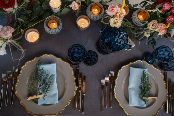 Düğün süsü masanın üstünde. Peçeteler mandallarla sıkıştırılır. Gri bir masa örtüsü. Mumlar ve çiçekler. Mavi şarap kadehleri. boho tarzı - Fotoğraf, Görsel