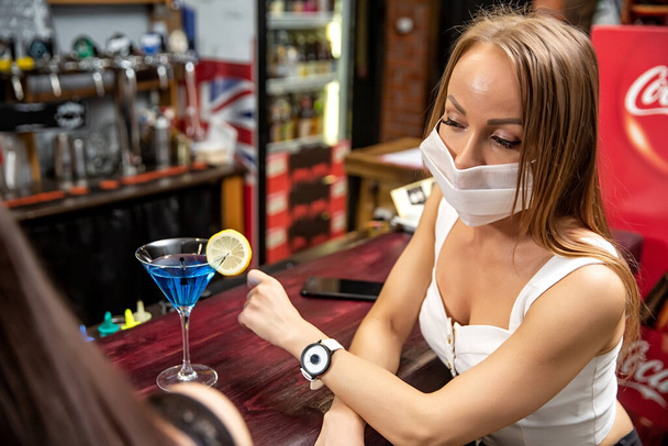 girl in a medical mask in a pub. girl in a restaurant. girl at the bar - Photo, image