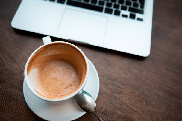 coffee cup at wooden table with laptop. copy space. close-up - Photo, Image