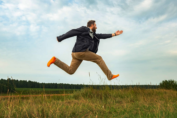 un uomo barbuto bianco in calzini arancioni vola sopra il suolo. corsa veloce attraverso il campo dopo un lungo soggiorno a casa in isolamento
 - Foto, immagini