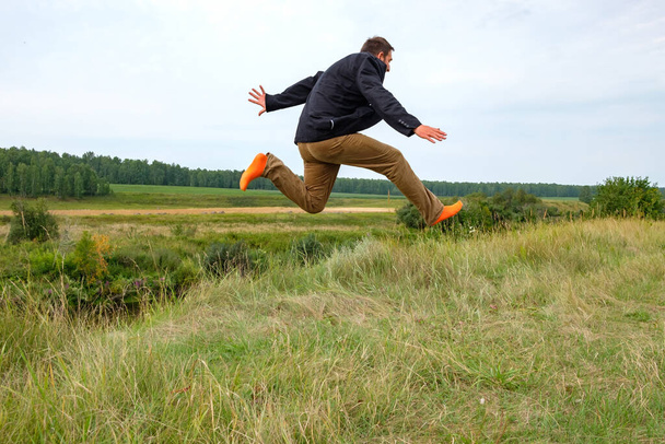 un uomo che correva per il campo in calzini arancioni saltò in alto con gioia. passi in avanti attraverso il campo
 - Foto, immagini