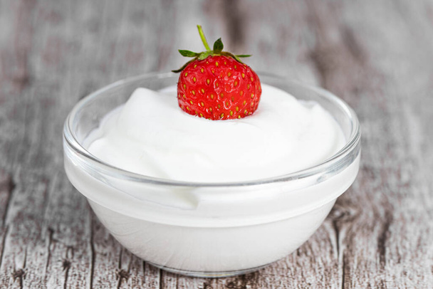 Frischer griechischer Bio-Joghurt mit Erdbeeren auf Holzgrund. - Foto, Bild