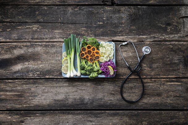 Sağlıklı beslenme ve yemek - bir tabak taze sebze steteskop yanında rustik ahşap tahtalara yerleştirilmiş. - Fotoğraf, Görsel