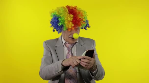Clown Geschäftsmann Freiberufler verliert Geld beim Spielen am Telefon Online-Spiele - Filmmaterial, Video