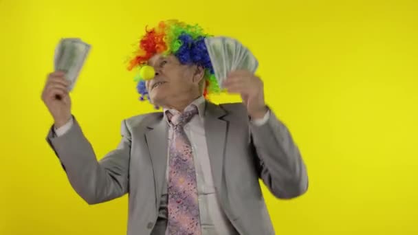 Elderly clown businessman entrepreneur boss dancing with money cash banknotes - Footage, Video
