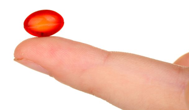 Woman's hand holding a red pill on white background close-up - Foto, Imagem
