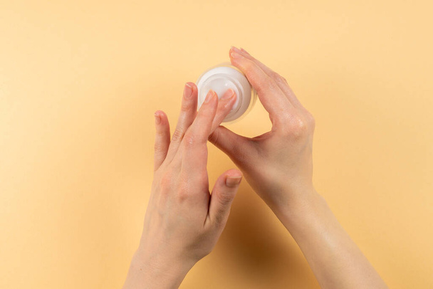 Hand cream and woman hands on a beige background. Copy space.  - Foto, afbeelding