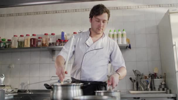 Koch kocht in einer Restaurantküche. Schöner Mann kocht Suppe in der Küche. Kaukasischer Koch arbeitet in Restaurantküche. - Filmmaterial, Video