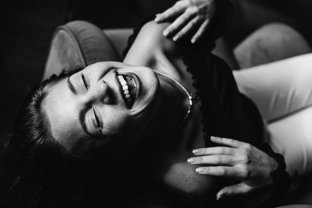 widok z góry dziewczyna w fotelu ze szczerym uśmiechem i zamkniętymi oczami, czarno-białe zdjęcie - Zdjęcie, obraz