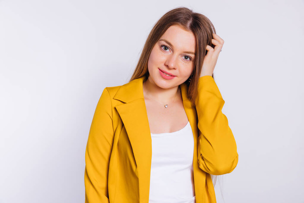  beautiful young woman with make-up in yellow jacket looking at camera on white background. - Photo, Image
