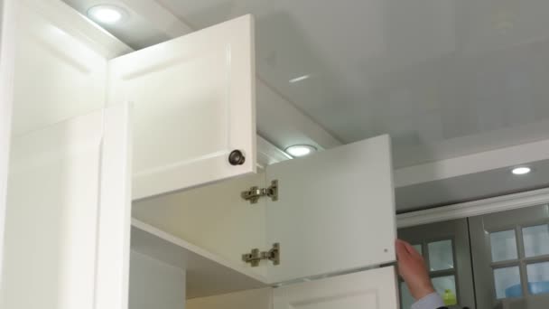Mans hand opens the kitchen bedside table. Empty kitchen bedside table in a white glossy kitchen. - Footage, Video