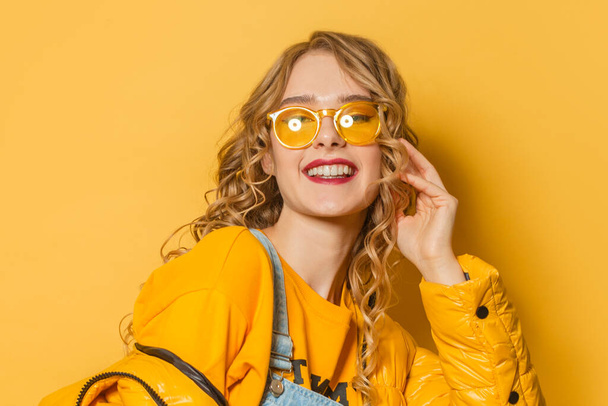 Joven mujer sonriente sobre fondo amarillo brillante, retrato de cerca
 - Foto, imagen