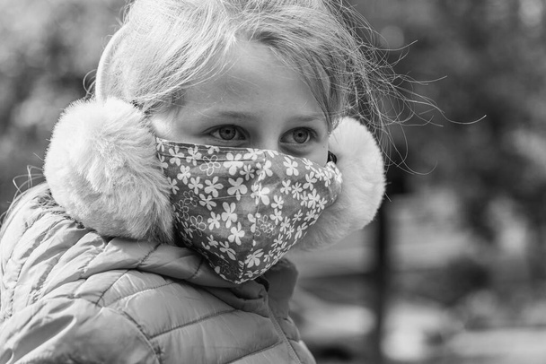 Porträt eines 9-jährigen Mädchens, das eine Maske trägt, während es auf der Straße geht. Pandemie, Virus, Isolation  - Foto, Bild