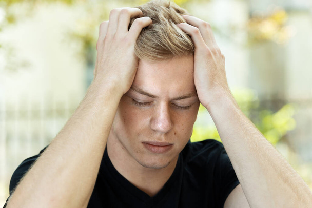 Portrét hezkého muže se stresem a bolestí hlavy s migrénou v parku - Fotografie, Obrázek