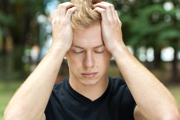 Portrait of a pretty man with stress and headache having migraine pain in the park - Φωτογραφία, εικόνα