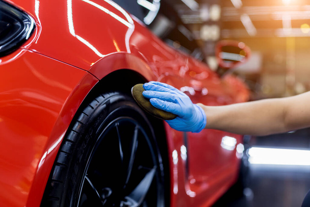 Car service worker polishing car wheels with microfiber cloth. - Foto, Bild