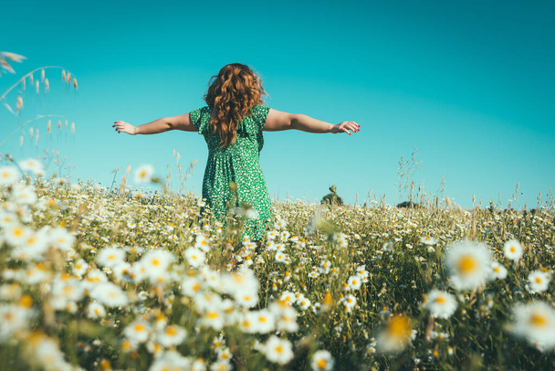 mujer en la espalda con los brazos abiertos en un campo de margaritas
 - Foto, imagen