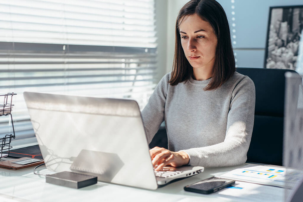 Woman busy working on laptop at office - Φωτογραφία, εικόνα