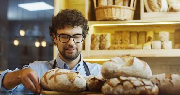 Portrait of handsome smiling baker working in bakery shop - Zdjęcie, obraz