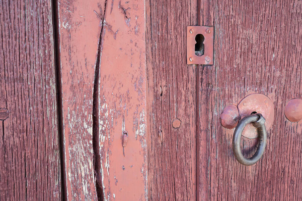 Παλιά κατεστραμένη κόκκινη βαμμένη ξύλινη πόρτα και κλειδαριά - Φωτογραφία, εικόνα