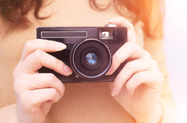 Old retro camera in the hands of photographer, close-up. Camera in female hands with yellow light. - Fotó, kép
