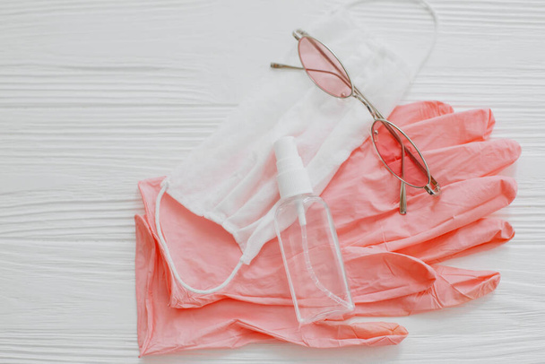 Gesichtsmaske, rosa Handschuhe, Antiseptikum und Desinfektionsmittel, Sonnenbrille auf weißem Hintergrund lagen flach. Sicheres Reisen im neuen Normalzustand. Schutzmaßnahmen gegen Coronavirus im Sommer 2020 - Foto, Bild