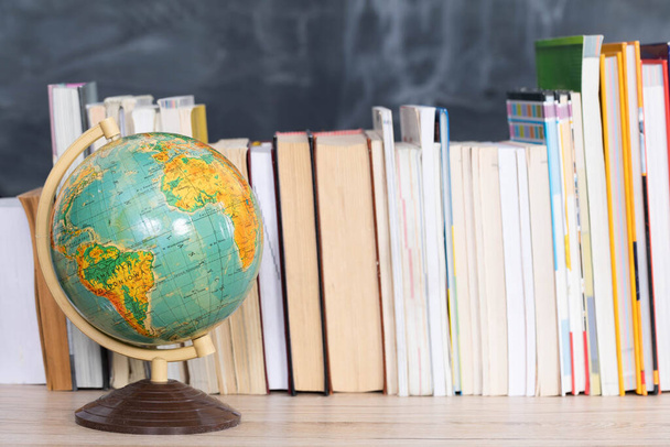 Geography lesson. A globe among a large number of school books. - Fotoğraf, Görsel