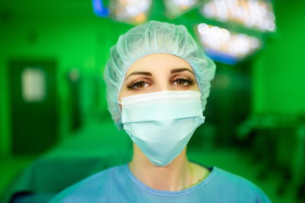 Kahverengi gözlü, cerrahi maskeli bir kadın doktor sana bakıyor. - Fotoğraf, Görsel