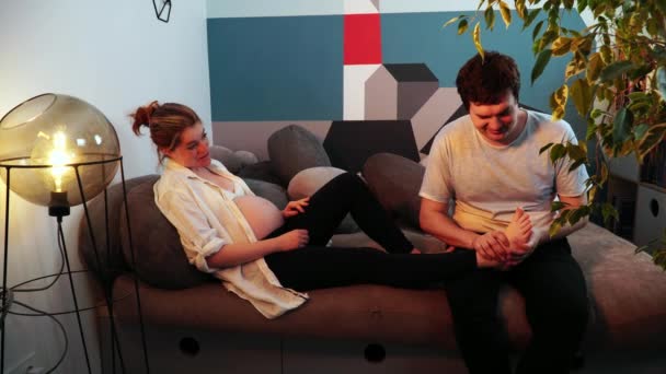 El hombre hace masaje de piernas a su esposa embarazada mientras están hablando
 - Metraje, vídeo