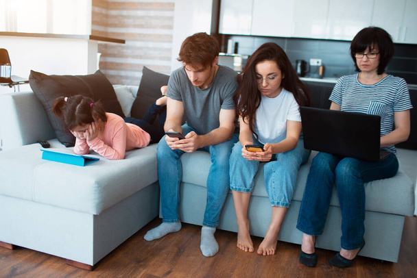 Big family at home. Everyone uses their own gadget. Dependence on social networks and mobile games. Tablet, smartphone and laptop instead of fun talking in the evening - 写真・画像